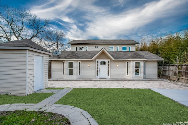 rear view of property featuring a storage unit, a lawn, and a patio area