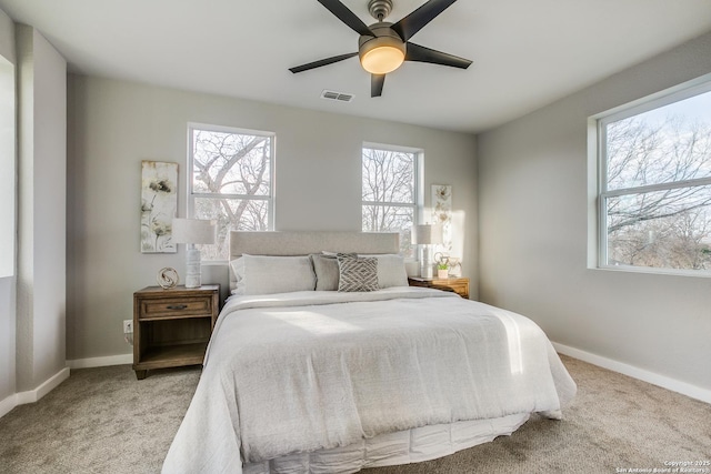 carpeted bedroom featuring multiple windows and ceiling fan