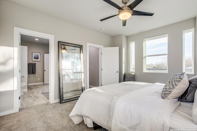 bedroom featuring ceiling fan, light colored carpet, and ensuite bath