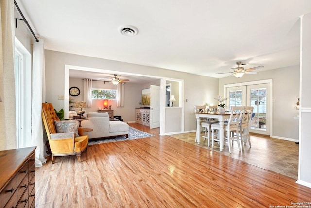 dining area with ceiling fan, light wood-type flooring, and french doors