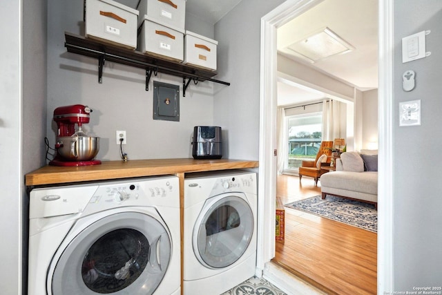 laundry room featuring wood-type flooring, electric panel, and washer and dryer