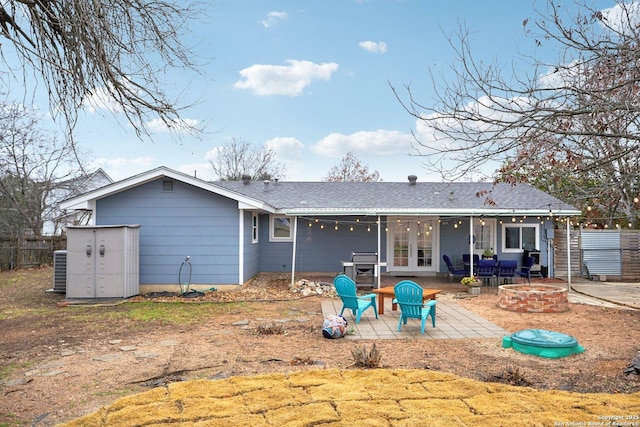 rear view of property with cooling unit, a patio, and a fire pit