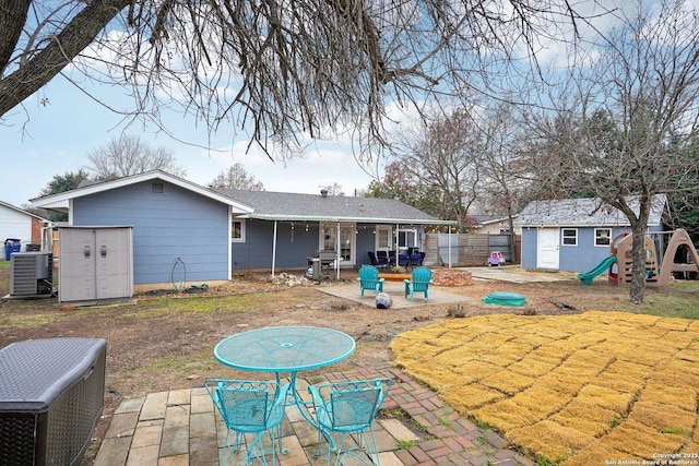 back of house with a patio, a playground, a shed, and central air condition unit