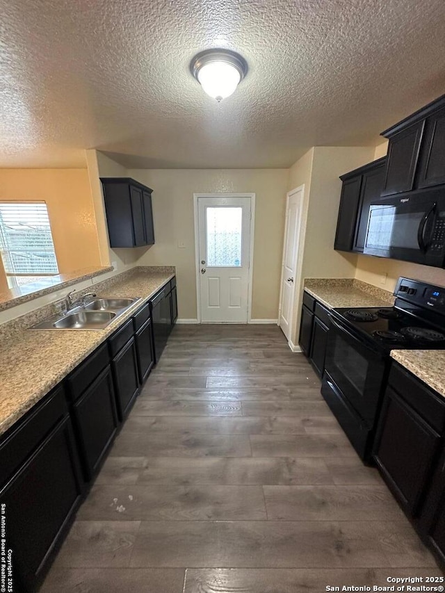 kitchen with dark hardwood / wood-style flooring, sink, black appliances, and a textured ceiling