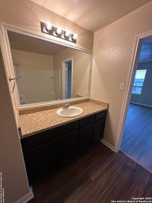 bathroom featuring vanity, hardwood / wood-style flooring, a textured ceiling, and walk in shower