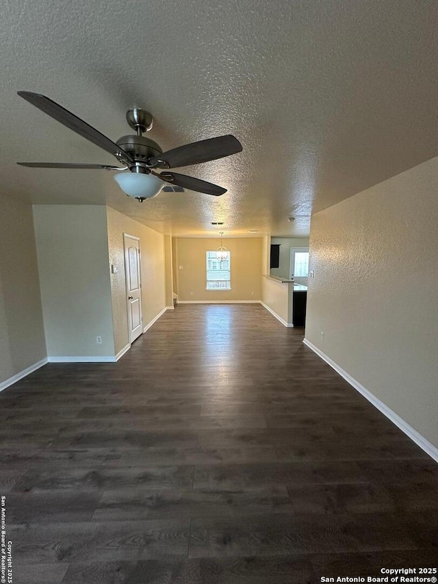 interior space featuring dark wood-type flooring, ceiling fan with notable chandelier, and a textured ceiling