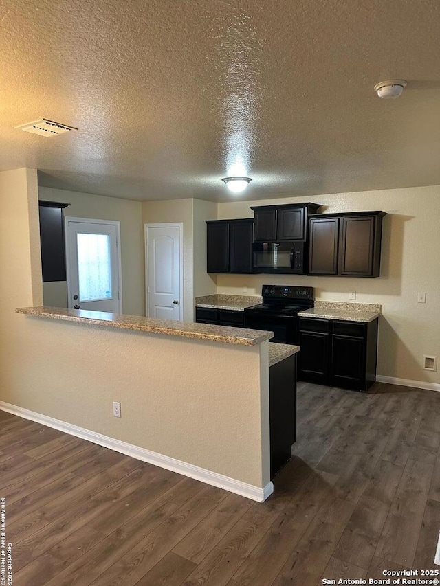 kitchen featuring dark hardwood / wood-style floors, kitchen peninsula, a textured ceiling, and black appliances