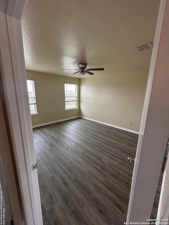 unfurnished room featuring ceiling fan, dark wood-type flooring, and a textured ceiling