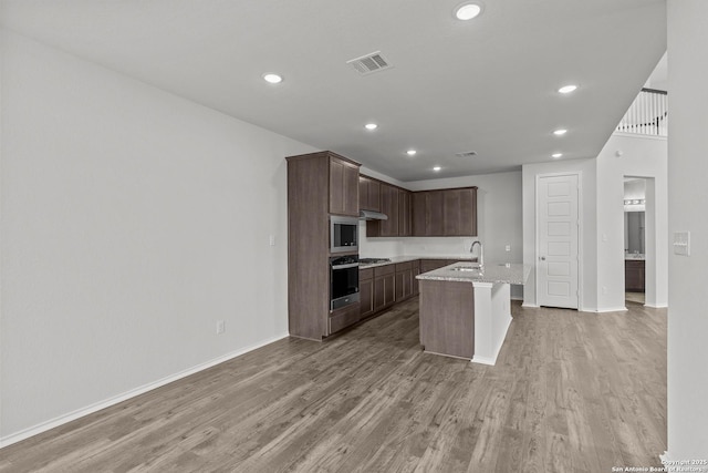 2439 Tinkerton, San Antonio, TX 78245 - kitchen featuring stainless steel appliances, a sink, light wood-style floors, recessed lighting, and a center island with sink