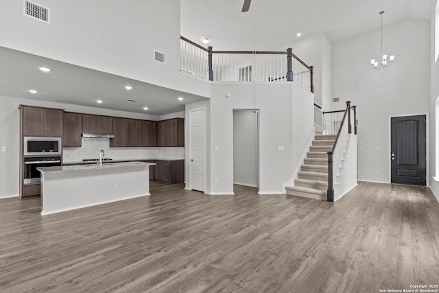 2439 Tinkerton, San Antonio, TX 78245 - kitchen with oven, built in microwave, a towering ceiling, under cabinet range hood, and a kitchen island with sink