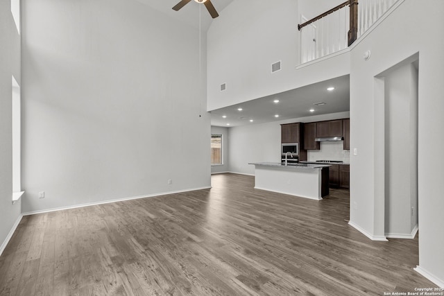 2439 Tinkerton, San Antonio, TX 78245 - unfurnished living room with ceiling fan, a high ceiling, dark wood-style flooring, and baseboards