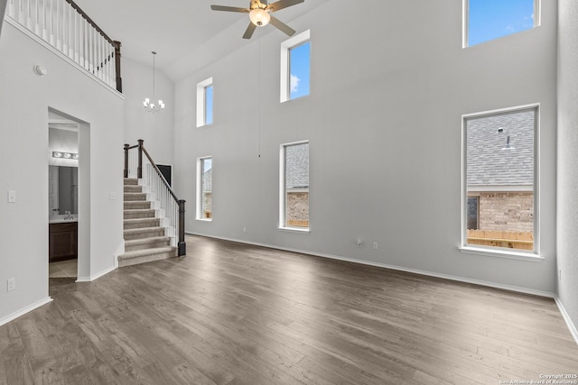 2439 Tinkerton, San Antonio, TX 78245 - unfurnished living room featuring a towering ceiling, stairway, a ceiling fan, healthy amount of natural light, and wood finished floors