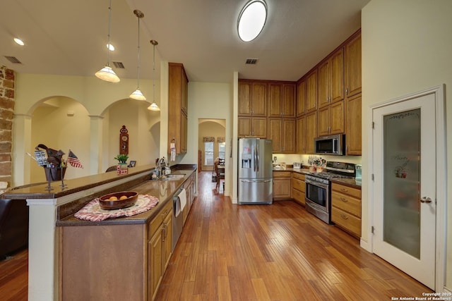 kitchen with sink, decorative light fixtures, appliances with stainless steel finishes, a kitchen breakfast bar, and kitchen peninsula