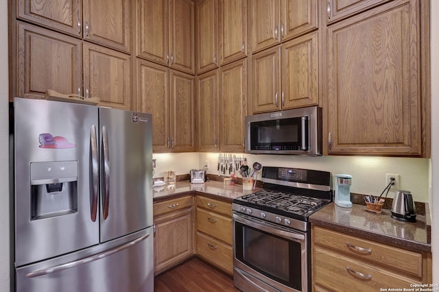 kitchen featuring stainless steel appliances, hardwood / wood-style floors, and dark stone counters