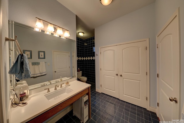 bathroom featuring tile patterned floors, toilet, vanity, and a tile shower