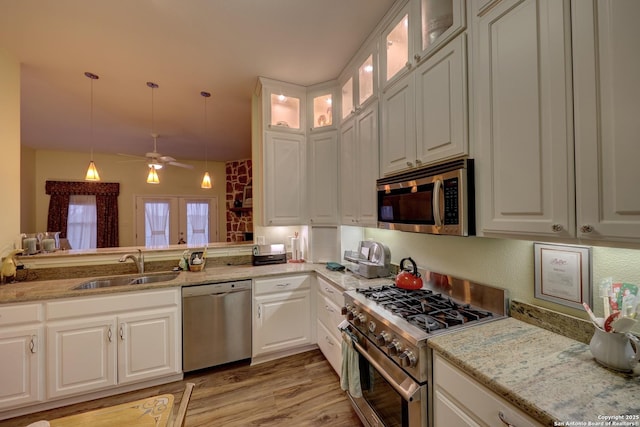 kitchen with appliances with stainless steel finishes, sink, pendant lighting, and white cabinets