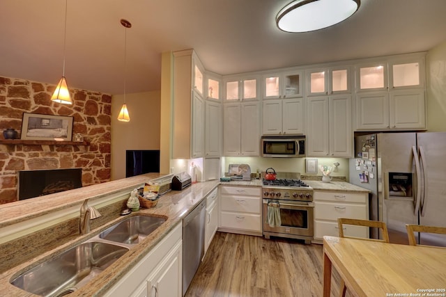 kitchen with sink, light stone counters, appliances with stainless steel finishes, pendant lighting, and white cabinets