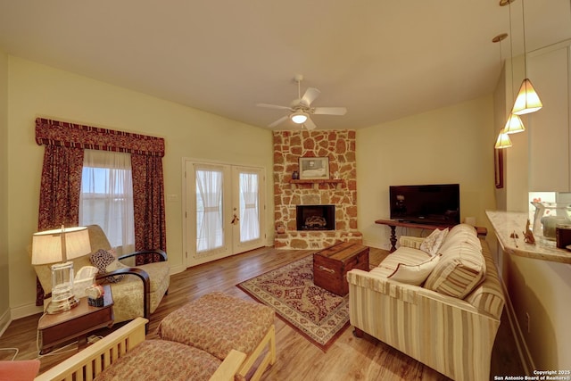 living room with french doors, lofted ceiling, hardwood / wood-style flooring, ceiling fan, and a fireplace