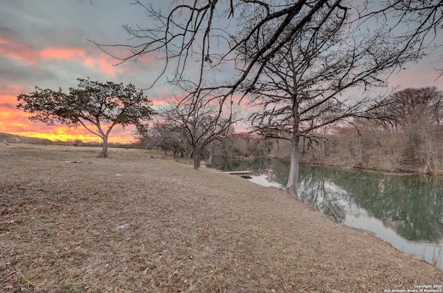 yard at dusk featuring a water view