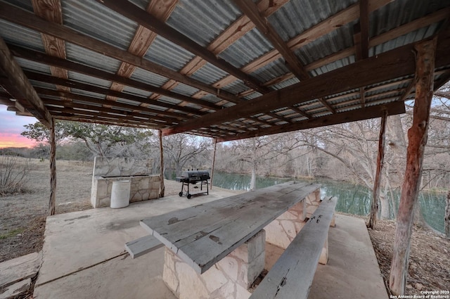 patio terrace at dusk featuring a water view and area for grilling