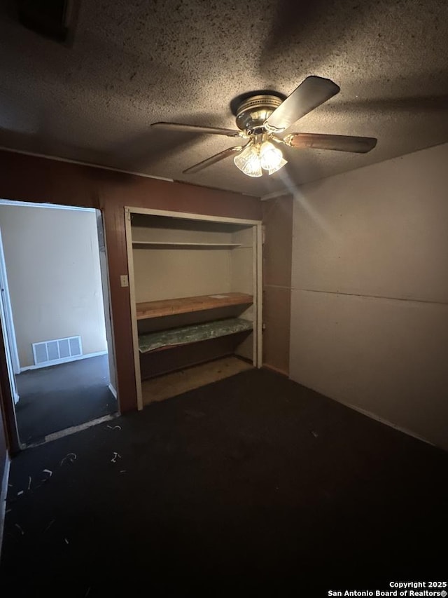 unfurnished bedroom with ceiling fan and a textured ceiling