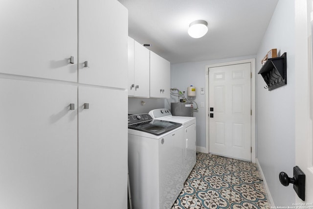 laundry room with water heater, washer and clothes dryer, and cabinets