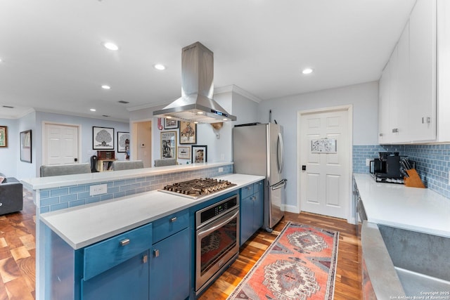 kitchen with stainless steel appliances, island exhaust hood, white cabinets, blue cabinets, and kitchen peninsula