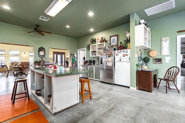 kitchen with ceiling fan, appliances with stainless steel finishes, white cabinets, and a kitchen bar