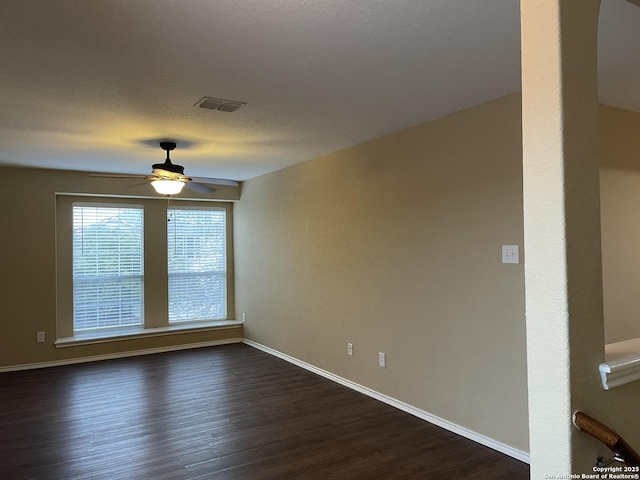 unfurnished room featuring baseboards, visible vents, a ceiling fan, dark wood-type flooring, and a textured ceiling