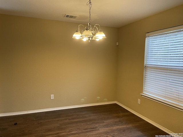 unfurnished room featuring visible vents, dark wood finished floors, a notable chandelier, and baseboards