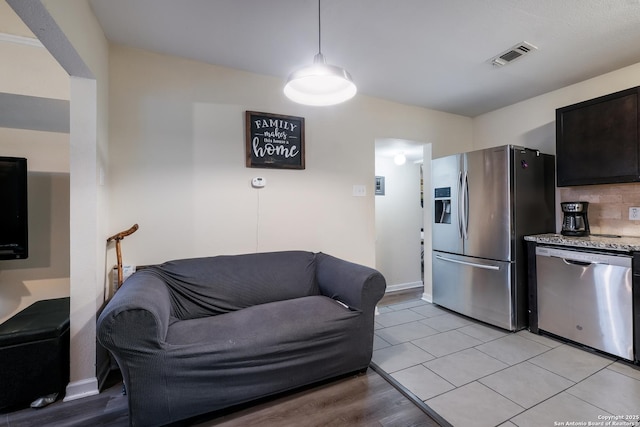 kitchen featuring light stone counters, backsplash, hanging light fixtures, and appliances with stainless steel finishes