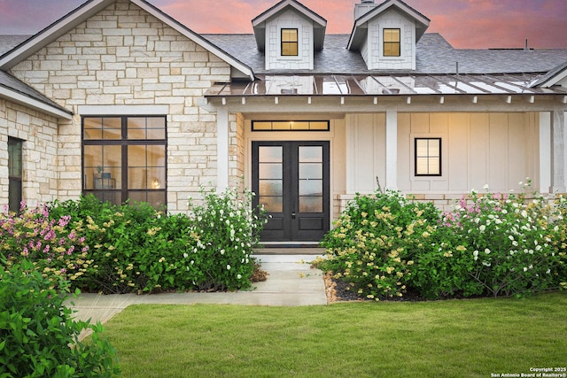 exterior entry at dusk featuring a lawn and french doors