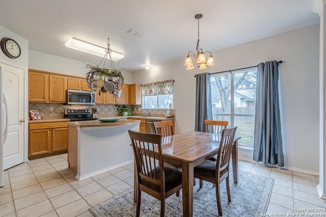 tiled dining area with sink, a chandelier, and a healthy amount of sunlight