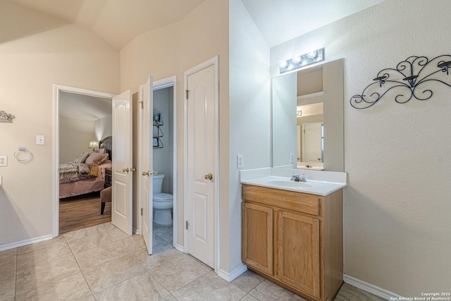 bathroom with tile patterned floors, lofted ceiling, toilet, and vanity