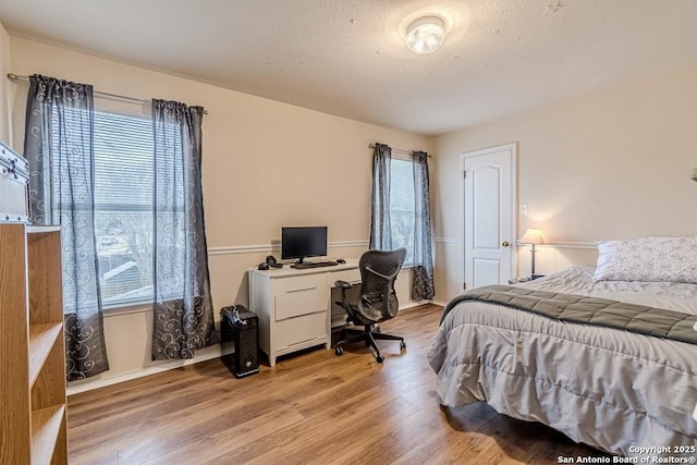 bedroom featuring multiple windows, light hardwood / wood-style flooring, and a textured ceiling