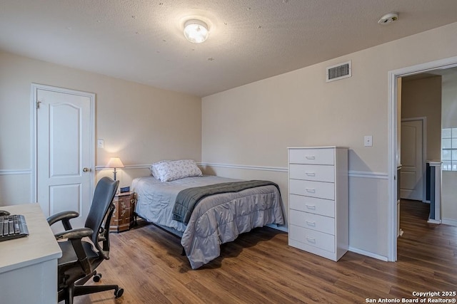 bedroom featuring dark hardwood / wood-style flooring and a textured ceiling