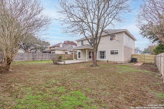 rear view of property featuring a yard, central AC unit, and a patio