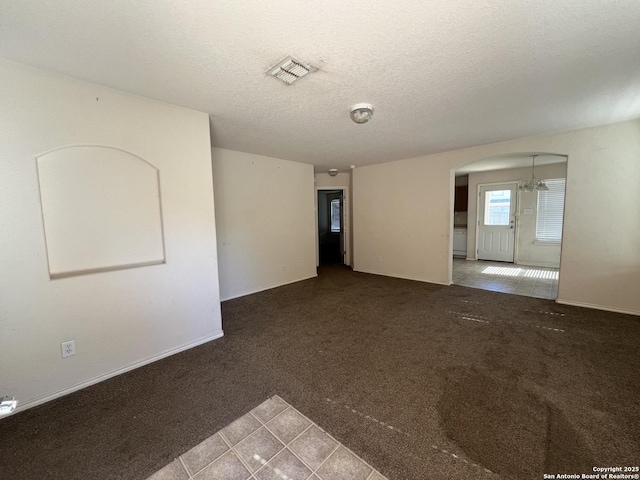 unfurnished room featuring carpet flooring, a textured ceiling, and a notable chandelier