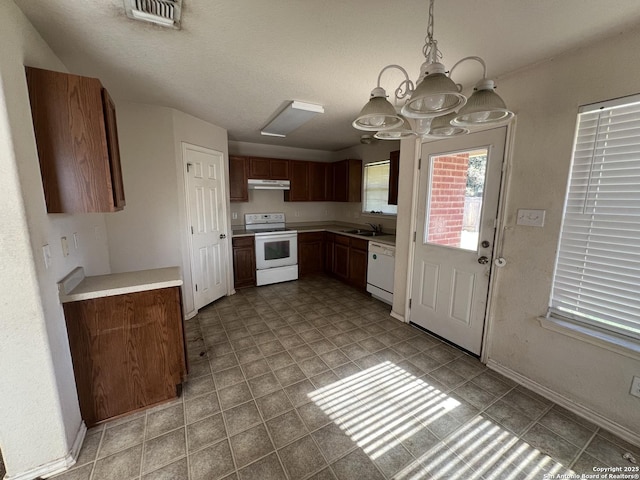 kitchen with white appliances, a chandelier, sink, and hanging light fixtures