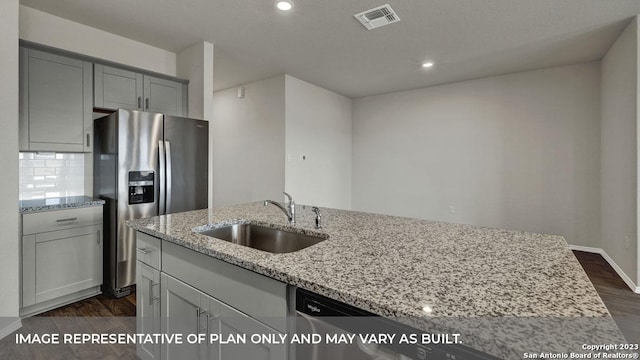 kitchen with light stone counters, dark wood-type flooring, sink, and stainless steel refrigerator with ice dispenser