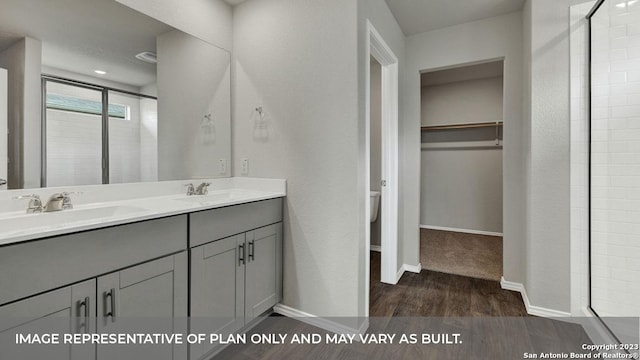 bathroom featuring vanity, wood-type flooring, a shower with shower door, and toilet