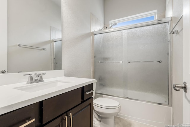 full bathroom with vanity, bath / shower combo with glass door, and toilet