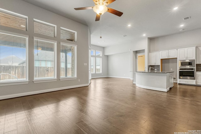 unfurnished living room featuring sink, dark wood-type flooring, and ceiling fan