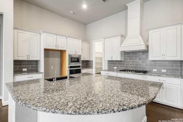 kitchen featuring stainless steel appliances, custom range hood, and white cabinets