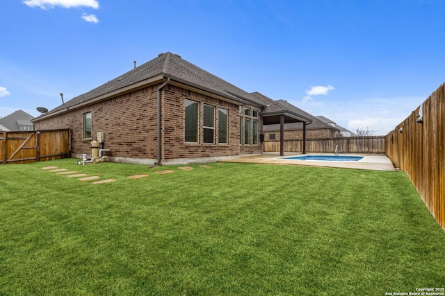 back of house featuring a fenced in pool, a yard, and a patio area