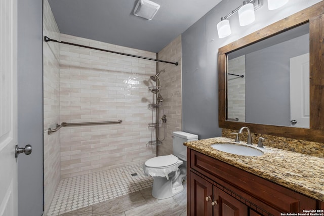 bathroom featuring vanity, toilet, and tiled shower