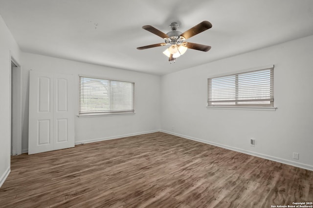 unfurnished room with ceiling fan, a wealth of natural light, and dark hardwood / wood-style flooring