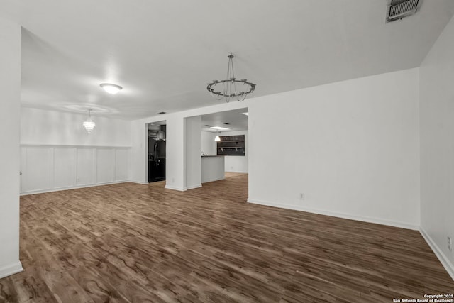 unfurnished living room with dark hardwood / wood-style floors and a chandelier