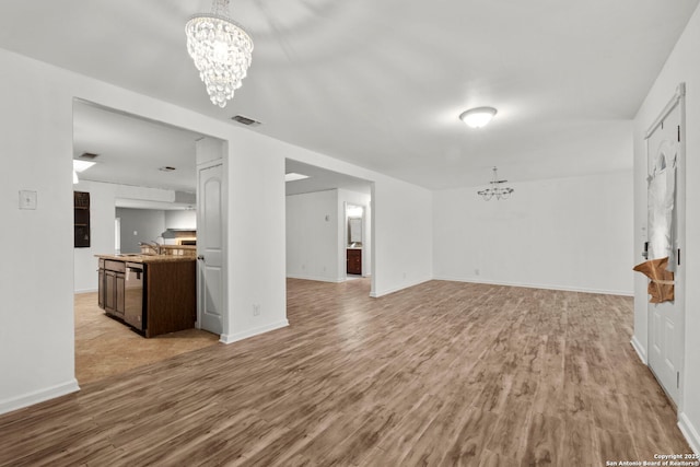 unfurnished living room featuring sink, light hardwood / wood-style flooring, and a notable chandelier