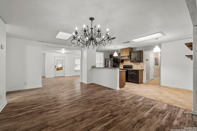 kitchen with backsplash, hanging light fixtures, light hardwood / wood-style floors, black appliances, and dark brown cabinets